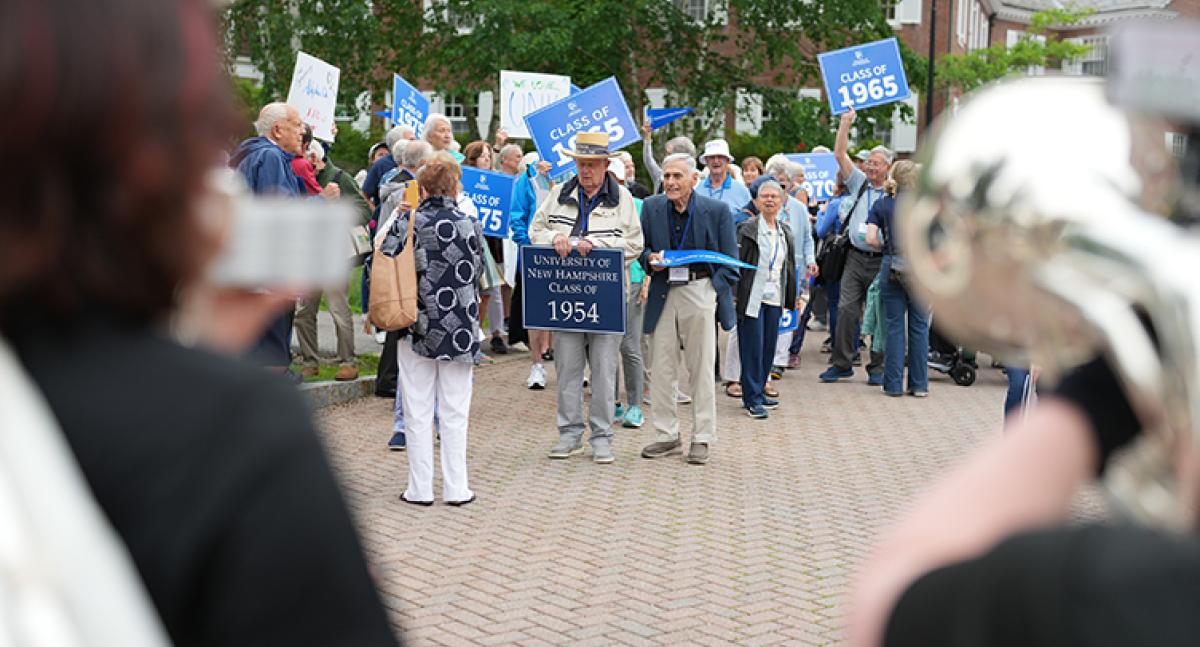 A band plays music as a group of alumni walk toward them 