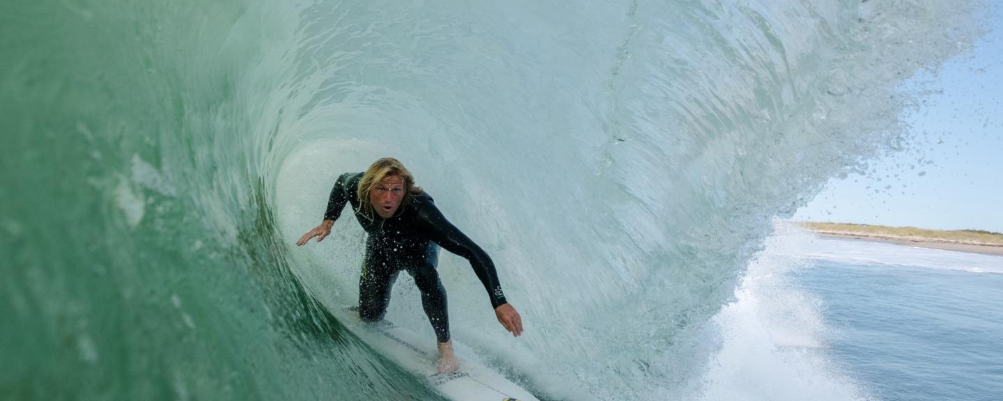 Image from inside a wave of a surfer ducking low on his board