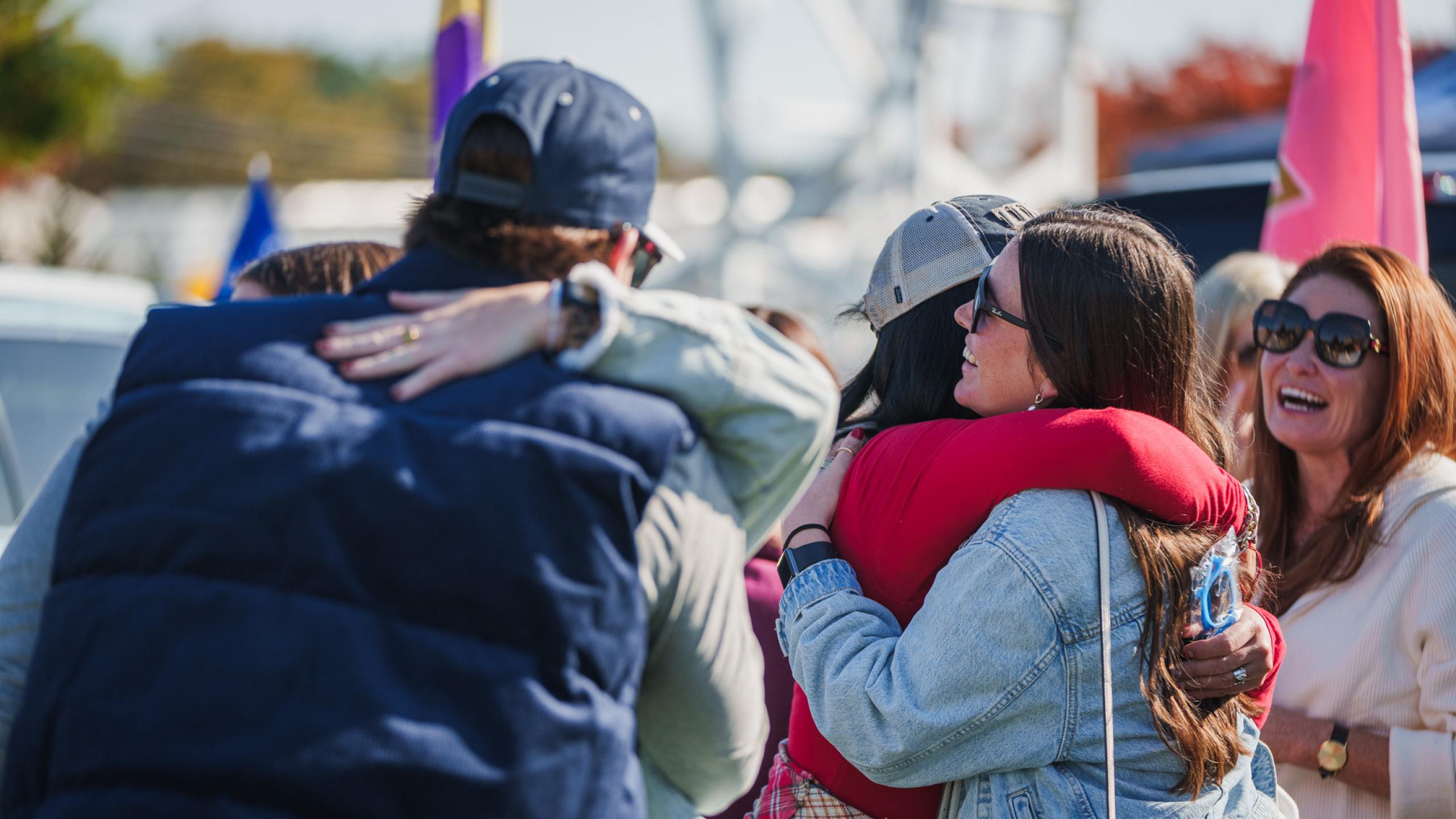 UNH alumni hugging their friends at Homecoming