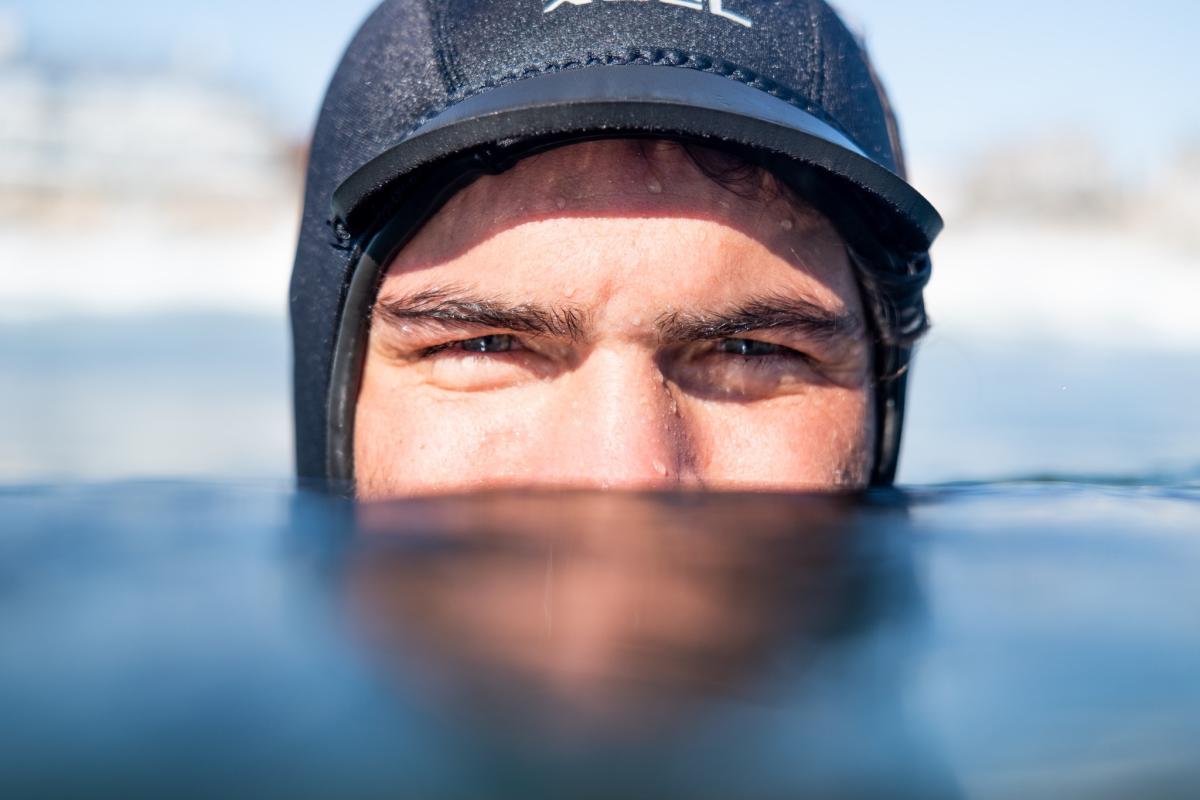 A man's nose and eyes are visible above water, with the rest of his face submerged
