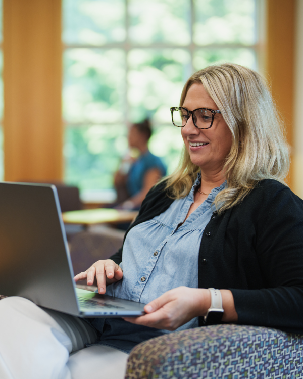 Female alumni sitting in a chair with a computer