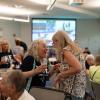 Two women smile as they greet each other in the middle of a crowded room