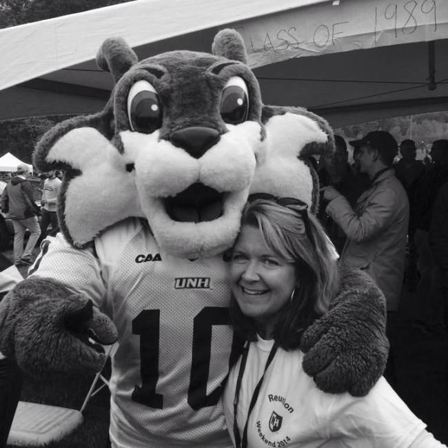 Photo of Betsy Murphy standing with the UNH mascot