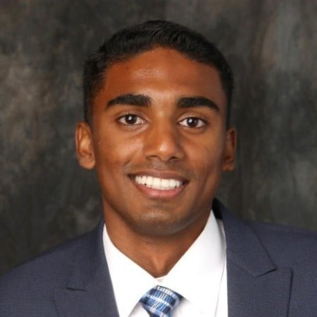 Headshot of a young man wearing a suit and tie, smiling